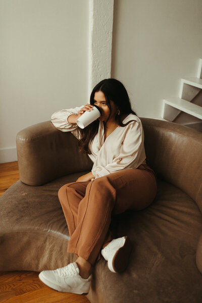 woman sitting on couch drinking coffee