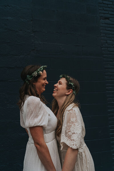 Wives stand facing each other laughing