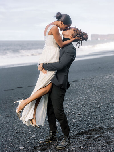 Stunning couple kissing on black sand beach Vik in Iceland
