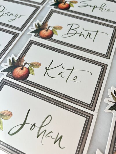 Green brush lettered place cards with apple illustration