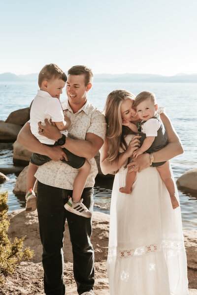 A mother and father hold their two sons and laugh with them at Lake Tahoe.