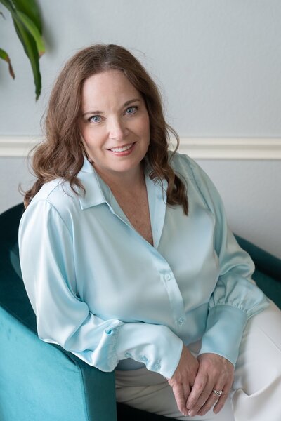 smiling woman in a blue shirt sitting in a chair
