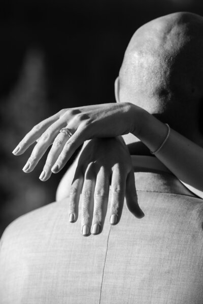 Close up of hands resting on a person's shoulder showing off wedding rings