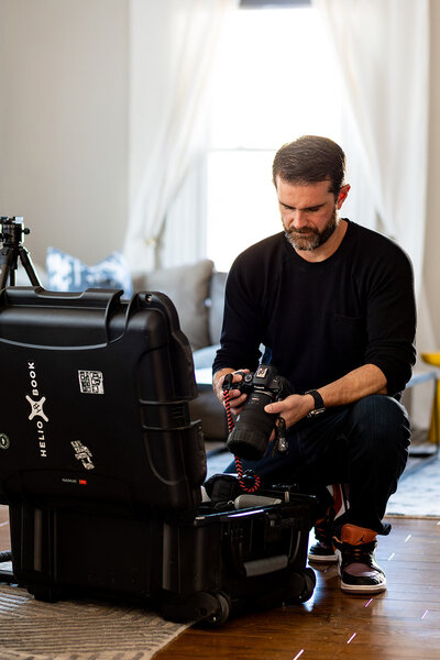 Branding photo of a man kneeling by photo equipment case.