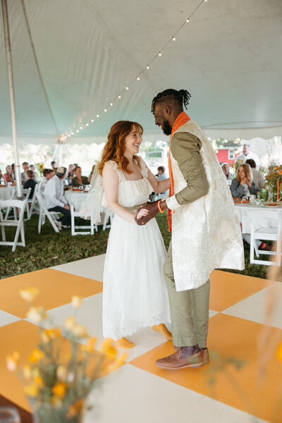 A wedding couple holding a bouquet of flowers standing in front of a painted wall