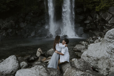 couple embrace in front of Jeongbang waterfall in Jeju Island