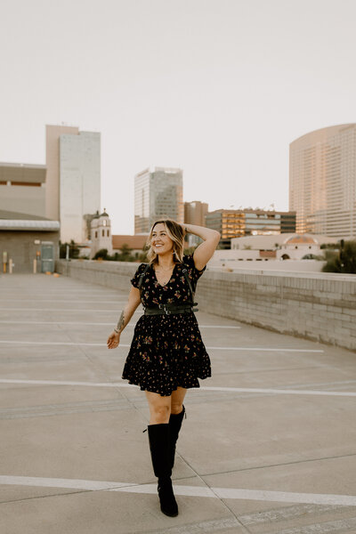 A woman with her hand on her head as she walks along  the roof of a parking garage.