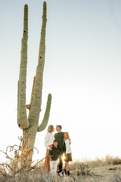 Family of four posing in the north scottdsale desert for a family photo next to a cactus