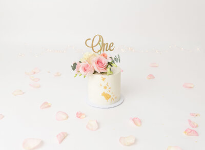 Untouched cake with gold leaf detail, fresh flowers, and a die-cut gold "one" take topper is captured prior to Brooklyn, NY cake smash.