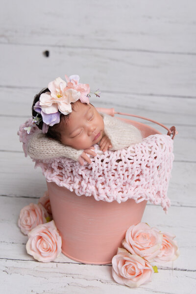 baby girl posed in a cute pastel bucket for her photoshoot