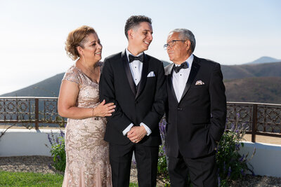 Groom smiling sweetly at dad while mom smiles at them both during Forth Worth wedding