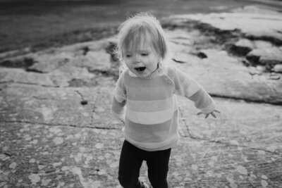 2 year old child running and smiling her hands spread in the air in Helsinki in Finland