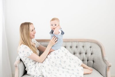 Mom sitting on couch holding toddler for his 1st birthday photos by Maryland Newborn Photographer Rebecca Leigh
