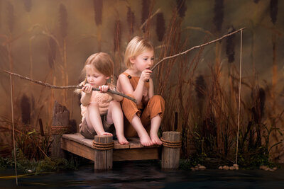 Whimsical milestone photography of two siblings fishing from a rustic dock, captured in Overland Park, Kansas. A charming scene for families seeking creative children’s photography in the Kansas City metro area.