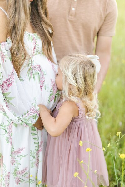 Child kissing mom's baby bump at maternity session at South Lake Park in San Marcos, California.