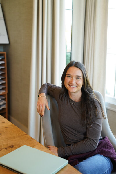 Megan sitting at a table and smiling at the camera confidently. 