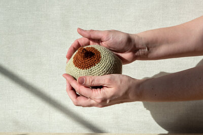 Hands holding a crocheted breast model used for breastfeeding education and lactation consultant support in New Jersey.