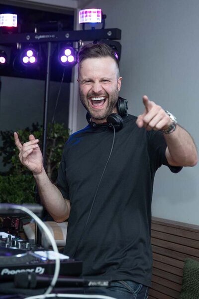 Male DJ pointing to camera keeping the party vibes going for all ages.