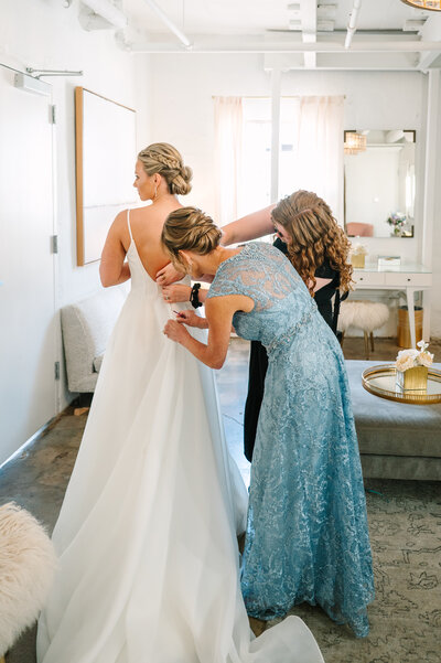 Mom and sister helping bride put dress on at Austin wedding