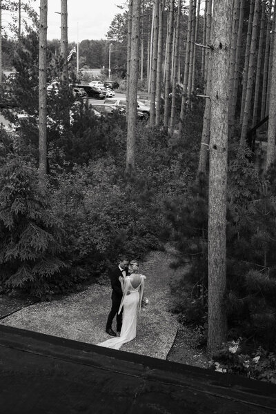 Bride and husband walking through the MN woods at their wedding venue in black and white