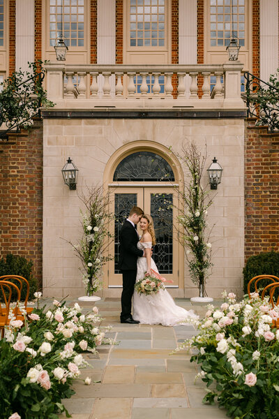 wedding couple standing at the end of a floral covered aisle