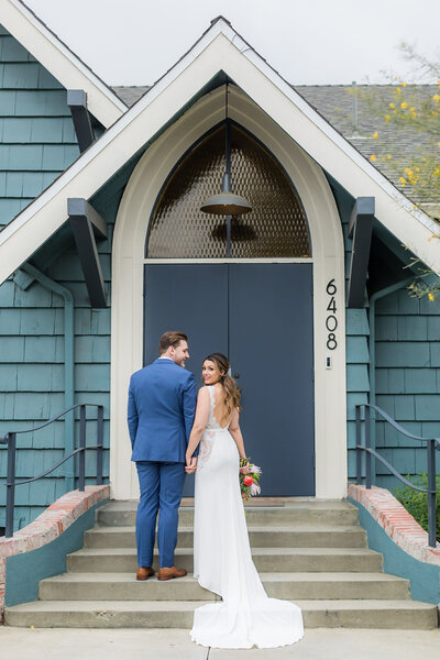 Bride holds hands with her groom and looks back over her shoulder smiling