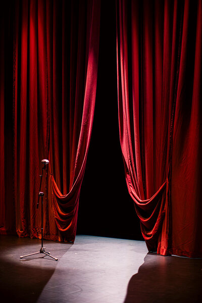 Image d'une scène ouverte avec des rideaux rouges dans une ambiance tamisée, en rappel à la cible de Fenicia Studio le secteur culturel et à son identité visuelle qui nous plonge dans l'ambiance théâtrale de l'opéra.