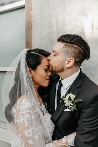 groom kissing brides forehead