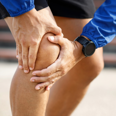 An elderly man holding his knee in pain and discomfort