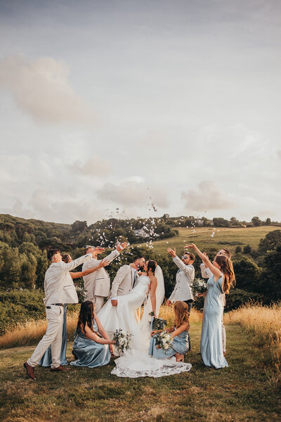 wedding party throw confetti over bride and groom