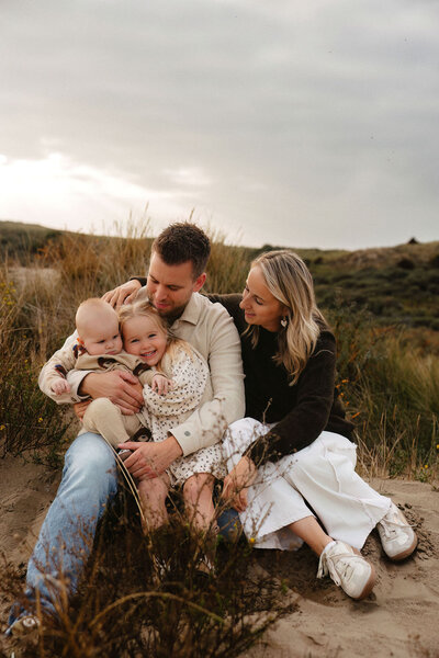 Gezinsfotoshoot in de duinen van Wassenaar met ouders en twee jonge kinderen in warm, natuurlijk licht door Linda Photography