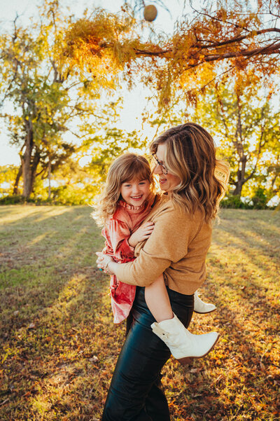Motherhood moment with mom hugging toddler tightly under soft evening light