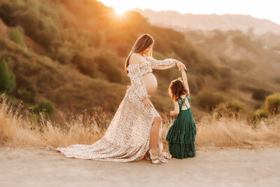 Maternity Photographer, pregnant mother twirling her daughter in the sun