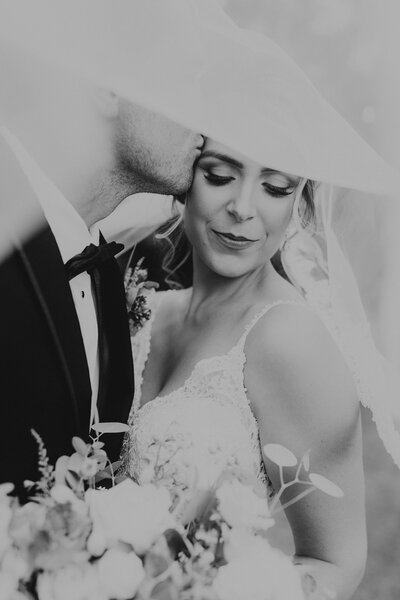 Bride leans on grooms shoulder looking off intothe distance