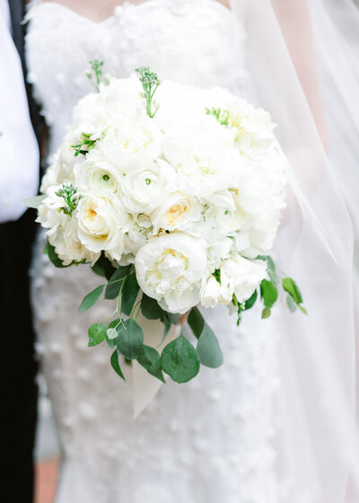 Elegant white bridal bouquet featuring roses, peonies, and eucalyptus leaves, captured in detail by fine art wedding photographer Abby Bell.