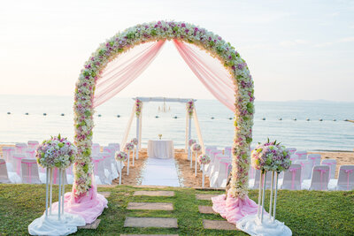 Outdoor Beach wedding ceremony site with pink details and arch florals