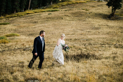 Destination wedding couple walk through meadow in Keystone, Colorado