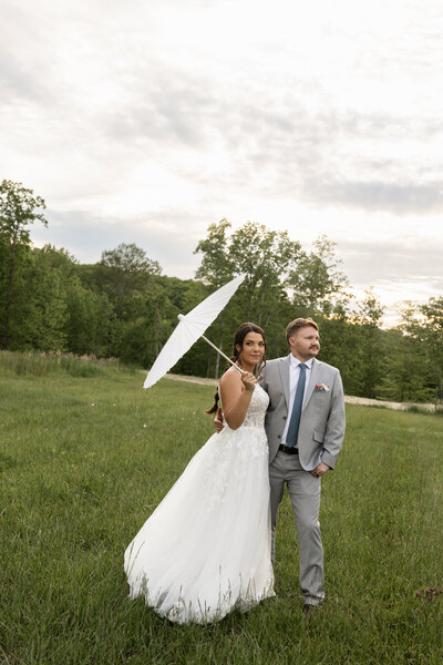 Bride and groom sharing a joyful moment under a stylish umbrella during their outdoor Kentucky wedding, photographed by Abby Dutra.