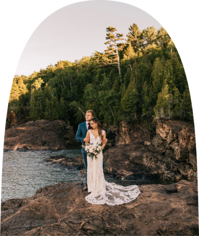 Bride and groom standing on a cliff overlooking a river on their wedding day
