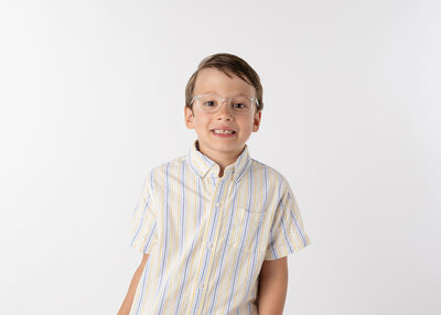 A young boy wearing glasses and smiling for his school photo.