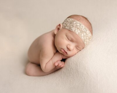baby girl with embroidered headband on white blanket