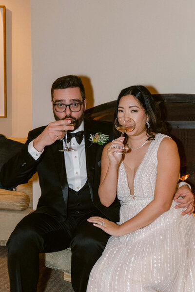 wedded couple at cocktail hour drinking champagne and gazing at the camera