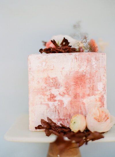 Sculptural wedding cake with a timeworn peach patina and rust foliage accents by Annie's Cakes