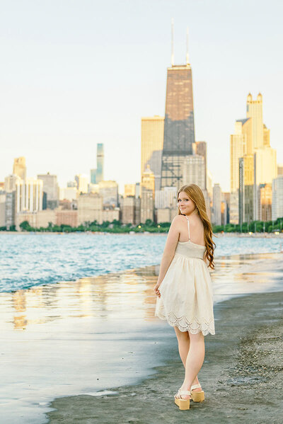 Senior girl in white dress walking along the concrete walkway at Chicago's North Avenue Beach