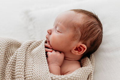 Newborn photoshoot baby girl laying on white blanket