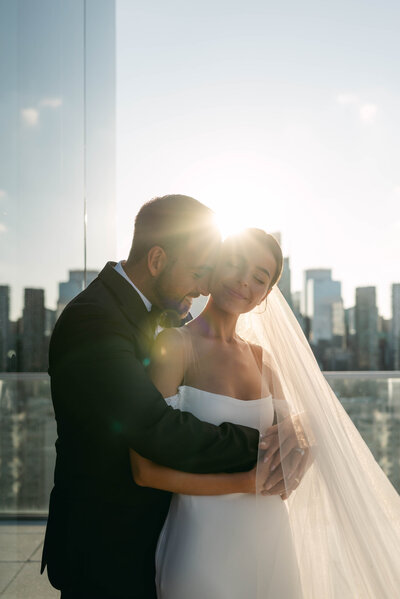 a bride and groom walk down a cobblestone path at a historic venue, the bride looks over her shoulder at the camera