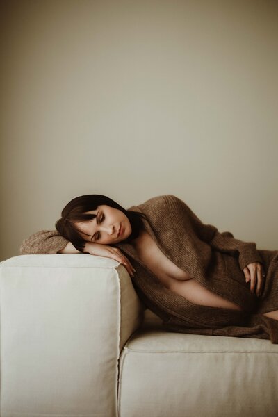Pregnant mother holding her bump in a moody studio session, photographed by Sydney maternity photographer Sophie Lea.