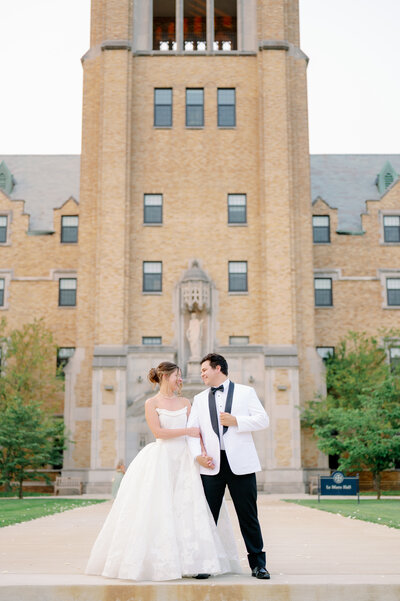 bride and groom smiling with their arms linked while standing on Saint Mary's campus