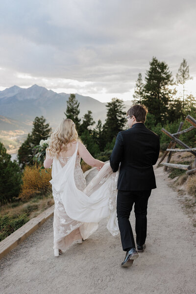 Bride and groom walk down Colorado trail during their fall elopement.