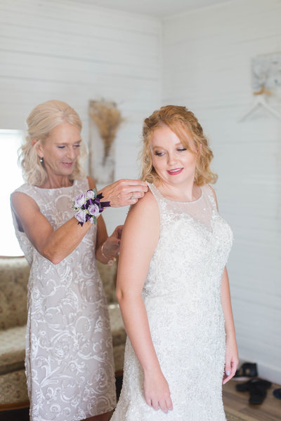 Mom helping bride into wedding dress